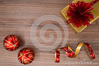 Gold gift box with red bouquet with red christmas bulbs and wrapping tape on a wooden table. Top view Stock Photo