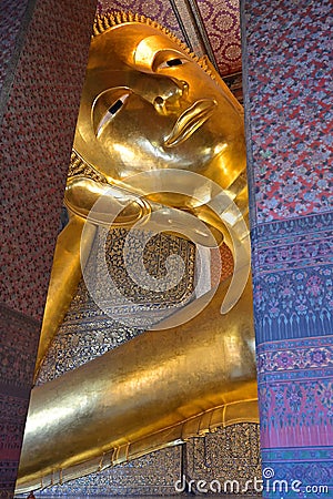 The gold gilded Reclining Buddha at Wat Pho has a serene gaze, and represents the Buddha's entry into Nirvana Stock Photo