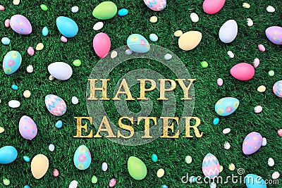 Gold Happy Easter text surrounded with Easter eggs and candy on grass Stock Photo