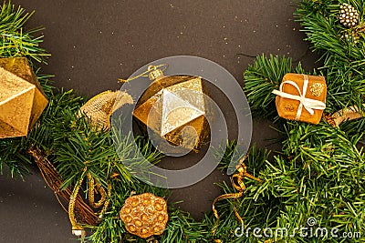 Gold ornaments and green garland on dark background. Stock Photo