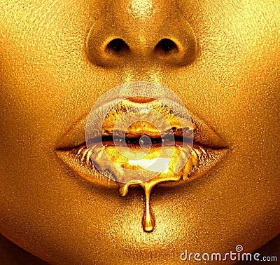 Gold paint drips from the lips, golden liquid drops on beautiful model girl`s mouth, creative abstract makeup Stock Photo