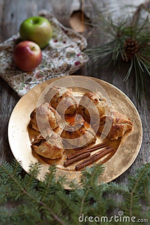 A gold plate of apple dumplings with cinnamon sticks and rustic props Stock Photo