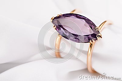 Gold ring with a large amethyst on silk fabric with copy space Stock Photo