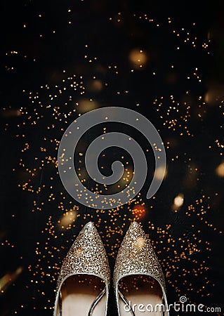 Gold shining women holiday pointy shoes on black background and shiny confetti stars around, holiday backdrop, selective focus, Stock Photo