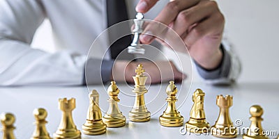 Gold and silver chess with player, Hands of businessman moving chess figure in competition to planning strategy to success play Stock Photo