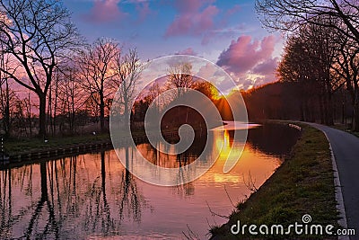 Gold sunset over river with sun rays, tree silhouettes and reflection on water Stock Photo