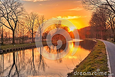 Gold sunset over river with sun rays, tree silhouettes and reflection on water Stock Photo