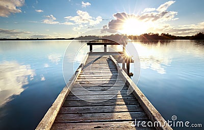 Gold sunshine over wooden pier on big lake Stock Photo