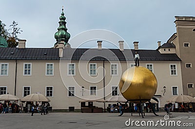 The golden ball statue with a man on the top sculpture, Kapitelplatz Square, Salzburg Editorial Stock Photo