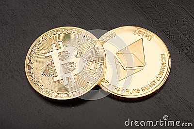 Golden Bitcoin and Ethereum on black wooden table Editorial Stock Photo