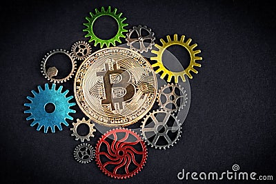 Golden bitcoin glowing among colorful cog wheels on black background with copy space. Cryptocurrency is the future - concept. Stock Photo