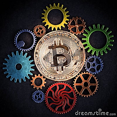 Golden bitcoin glowing among colorful cog wheels closeup, square format. Stock Photo