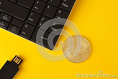 Golden bitcoin, keyboard and flash drive on a yellow background Stock Photo