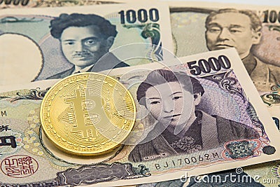 Golden Bitcoin on pile of many type japan banknotes background. Stock Photo