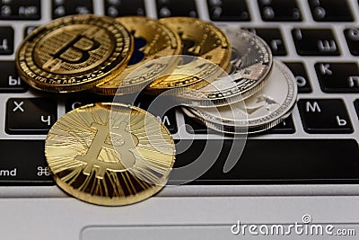 Golden bitcoins lies on silver notebook keyboard Editorial Stock Photo