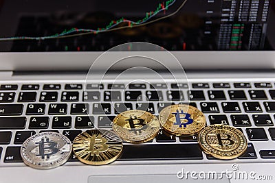 Golden bitcoins lies on silver notebook keyboard Editorial Stock Photo