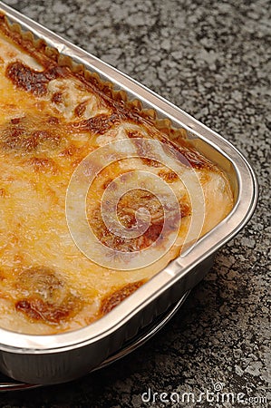 A golden brown lasagne displayed in a foil tin holder Stock Photo