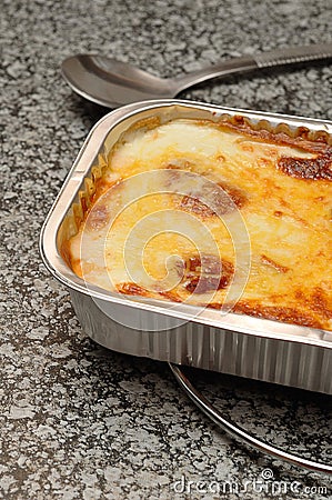 A golden brown lasagne displayed in a foil tin holder Stock Photo