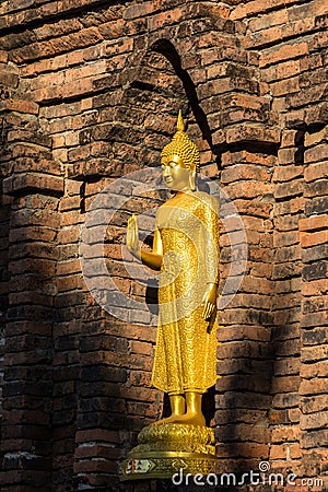 Golden Buddha in front of ancient Maha Chedi in North of Thailand Stock Photo