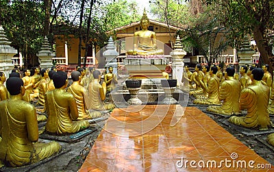 Golden Buddha and monks statues in Buddhist temple Stock Photo