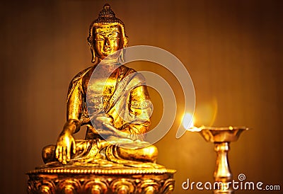 Golden Buddha with oil lamp Stock Photo
