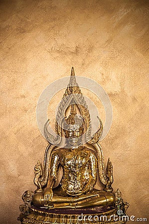 Golden Buddha Sculpture on goldish wall background - Vertical Stock Photo