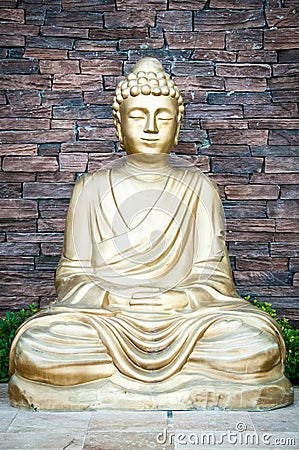 Golden Buddha statue against a brick wall background Stock Photo