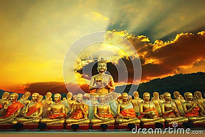 golden buddha statue in buddhism temple thailand against dramatic sun rising with ray beam background Stock Photo