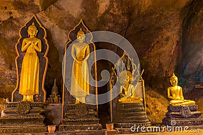 Golden buddha statues along the wall inside the cave Stock Photo