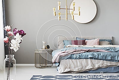 Golden chandelier above king size bed with blue, beige and pastel pink sheets Stock Photo