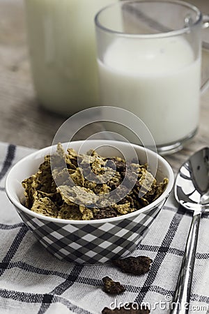 Golden and chocolate cornflakes in a bowl and a glass of milk on the wooden table Stock Photo