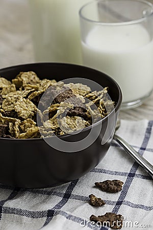 Golden and chocolate cornflakes in a bowl and a glass of milk on the wooden table Stock Photo