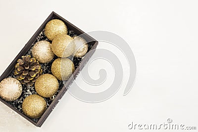 Golden Christmas balls in a wooden crate on a white rustic wooden background. Top view Stock Photo