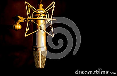 Golden color microphone detail in music and sound recording studio, black background, closeup Stock Photo