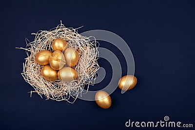 Golden colored Easter eggs in decorative nest on dark blue background. Copy space. Stock Photo