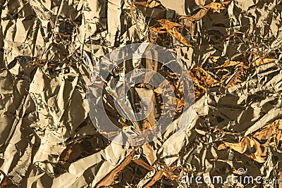 Golden crumpled shiny metallic paper. Yellow tinfoil texture for holiday. Glossy crinkled kitchen foil background Stock Photo