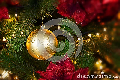 Golden decorative ball hanging on a branch of a Christmas tree in the light of garland. Phot backdrop decoration for Christmas Stock Photo