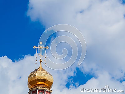 The Golden dome of an Orthodox temple on background of blue sky and clouds. Golden cross on the dome of the temple Stock Photo
