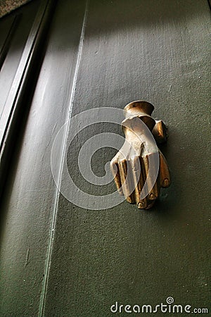 Golden doorknocker with hand shape on old green wooden door Stock Photo