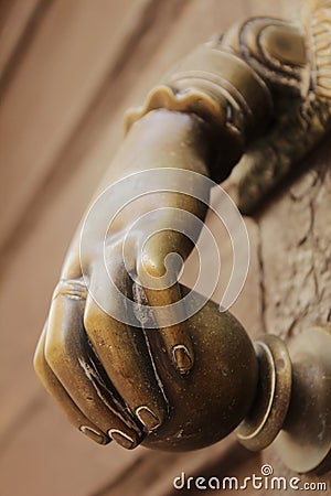 Golden doorknocker with hand shape on old wooden door Stock Photo