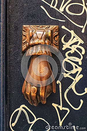 Golden doorknocker with hand shape on old wooden door Stock Photo