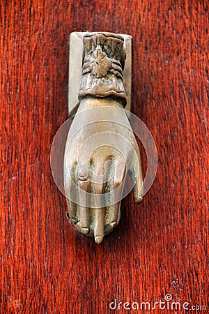 Golden doorknocker with hand shape on old wooden door Stock Photo