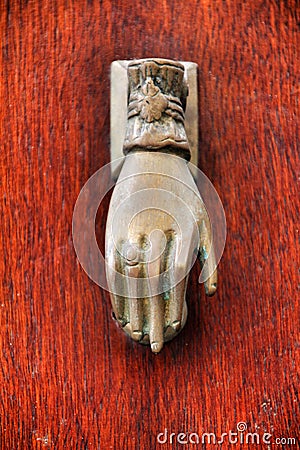 Golden doorknocker with hand shape on old wooden door Stock Photo