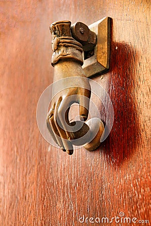 Golden doorknocker with hand shape on old wooden door Stock Photo