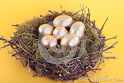 Golden eggs in bird nest over yellow Stock Photo