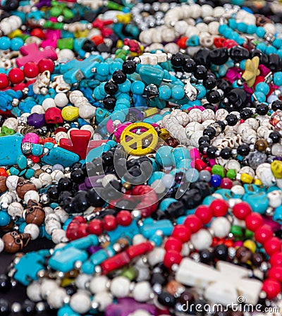 A golden peace sign pendant on top of a pile of jewelry. Editorial Stock Photo