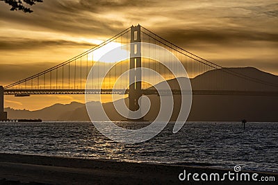 Golden Gate Bridge at dusk with a gpld brown pastel sky and an outline of a kite surfer Stock Photo