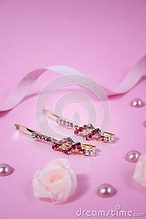 Golden hairpins with pink gemstone and pink polka dot ribbon on pink background Stock Photo