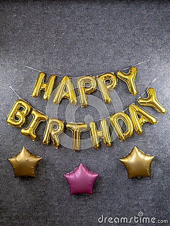 Golden inscription happy birthday and big stars on a gray wall Stock Photo