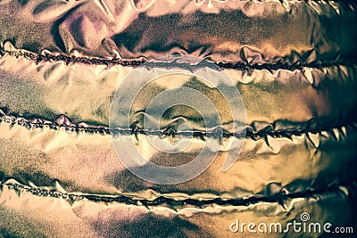 Golden iridescent texture of the bologna fabric of the quilted youth jacket. Trendy style background. Stock Photo